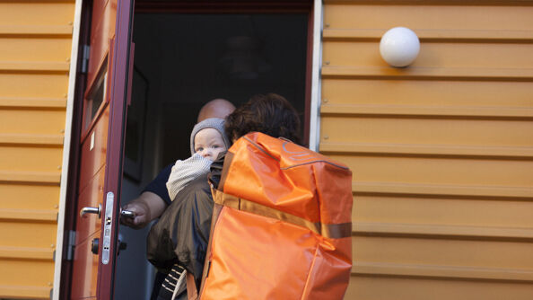 En kvinne og et barn på vei inn i et hus