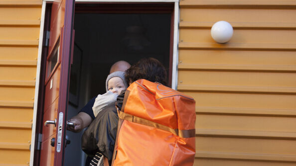 En kvinne og et barn på vei inn i et hus