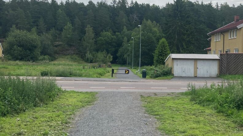 Utendørs, gruslagt turvei som krysser asfaltert bilvei, trær i bakgrunnen.  Viser hvor turveien krysser Hellerudveien hvor gangfeltet skal flyttes til slik at en kan følge turveien direkte videre på begge sider. 