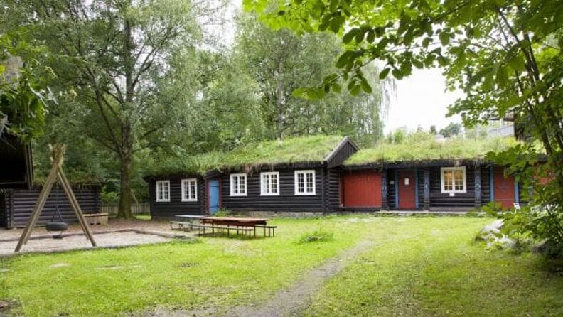 Barnehagens uteområde med sandkasse, benker og lekestativ