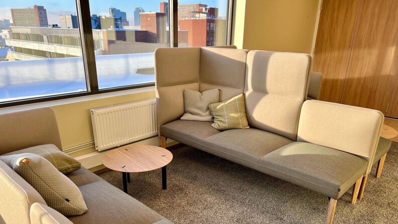 To sofaer  og et lite bord foran store vinduer med utsikt.