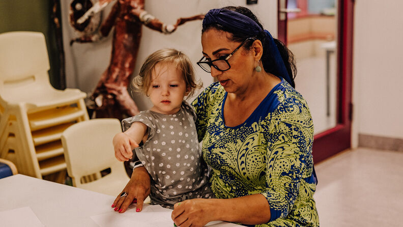 Et lite barn sitter på fanget til en voksen dame,