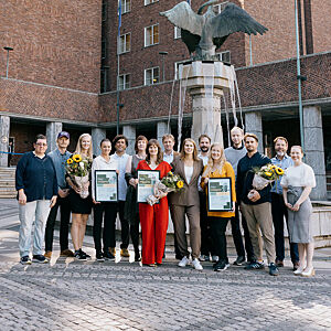 Mange mennesker foran Oslo rådhus med diplom og blomster