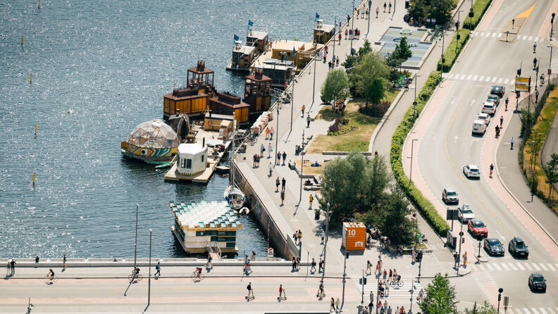Mennesker i Bjørvika og Langkaia i Oslo med flytende badstuer sett fra høyden.