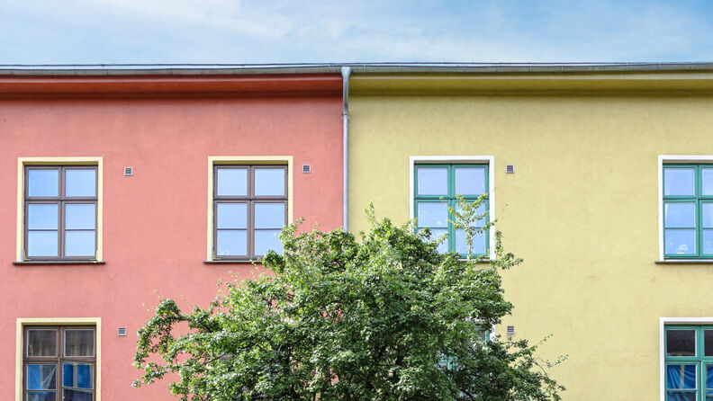 Boligblokk med grønt tre i midten av bildet.