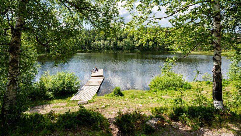 To personer sitter på en badebrygge på Lille Tryvann.