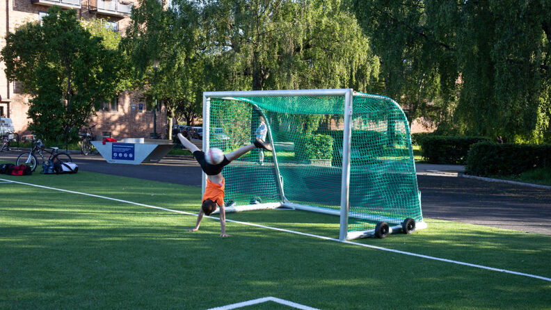 En person står på henda ved et fotballmål på kunstgressbanen like øst for Kampen park.