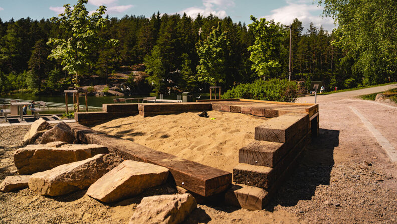 Sandkasse med stein og treverk rundt på Svarttjern lekeplass.