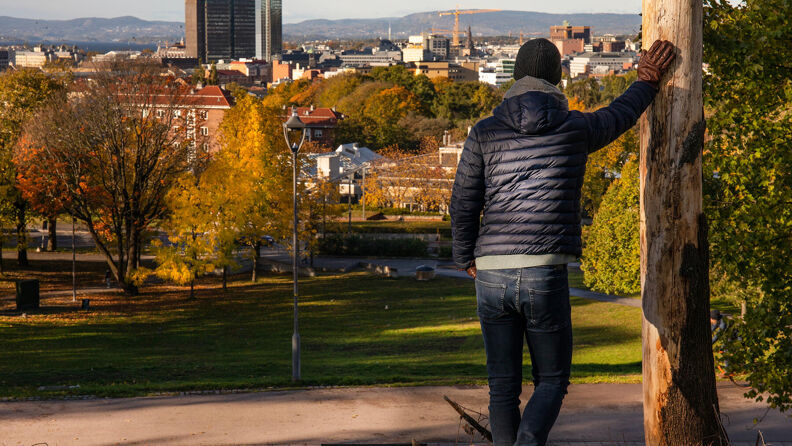 En mann står lent mot en stolpe og ser på utsikten øverst i Tøyenparken.