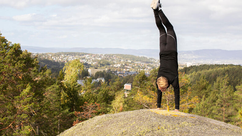 En mann står på hendene på utsiktspunktet på St. Hansåsen.
