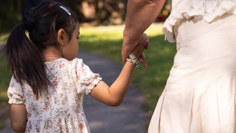 Barn leier hånden til en ansatt i en barnehage.