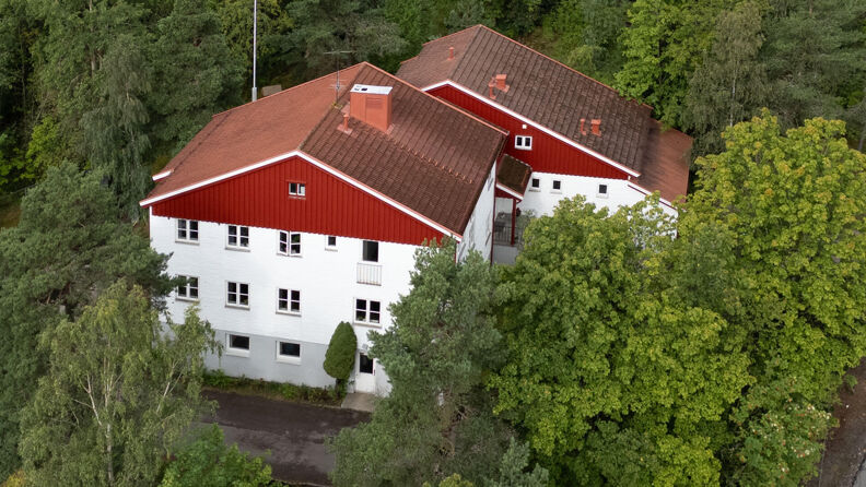 Rødt og hvitt hus omgitt av trær