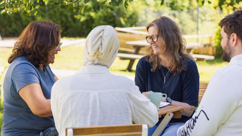 To barnehageansatte og to foreldre sitter rundt et bord og prater sammen.