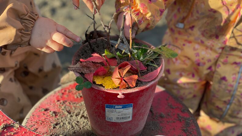Barn som leker med sand og høstblader 