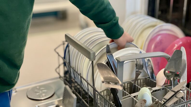 Barn som setter inn tallerken i oppvaskmaskinen