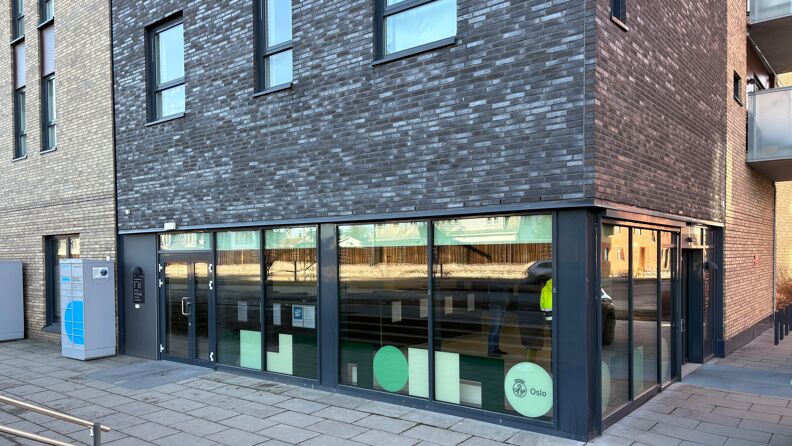 Gatehjørne, store vinduer med grønne symboler.