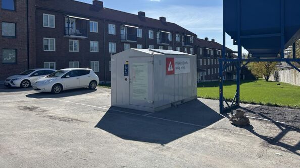 Grå container foran brunt murbygg