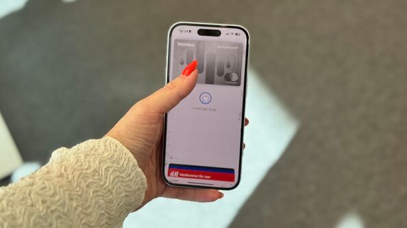 Hand holding iPhone with Nordea card showing in Apple pay