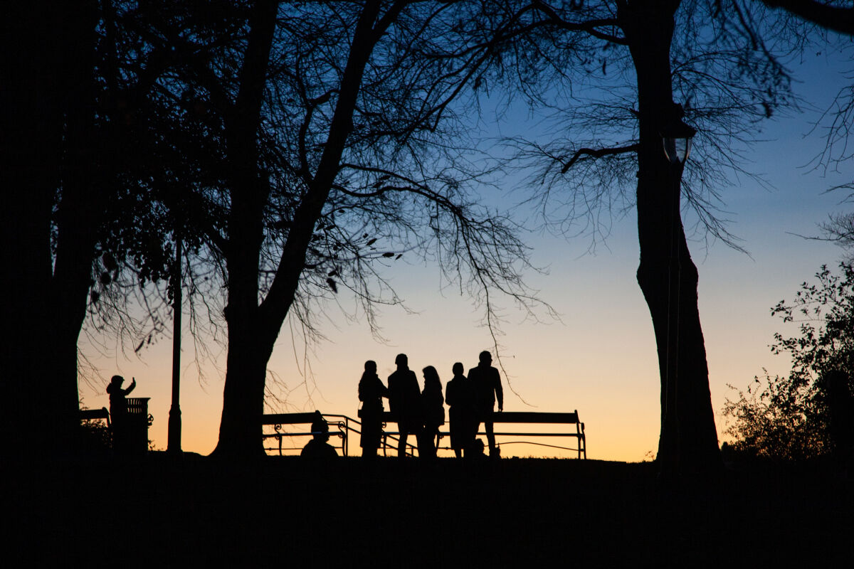Silhuetter av mennesker i en park i solnedgang