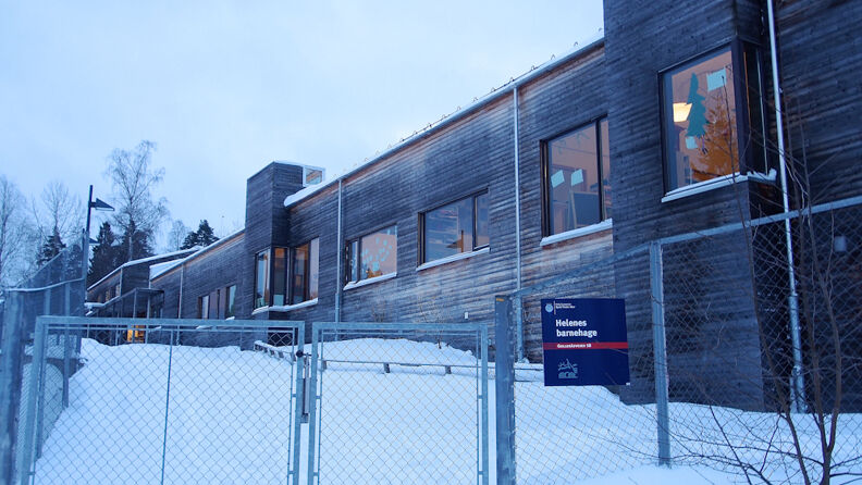 Inngangspartiet til barnehagen med grå stålport, snø og mørk gråmalt barnehage på siden